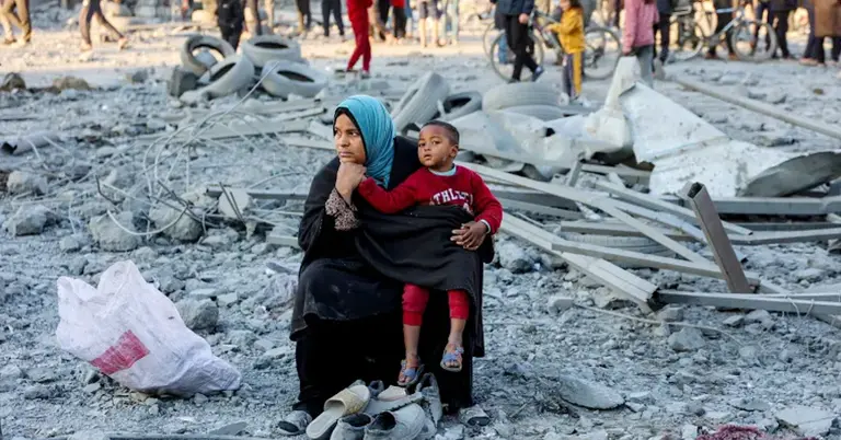 ফিলিস্তিনের ধ্বংসস্তূপের মধ্যে শিশুকে কোলে নিয়ে এক মা